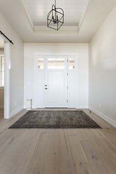 an empty room with a chandelier and white doors in the center is shown