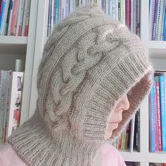 a person wearing a knitted hat in front of a book shelf filled with books