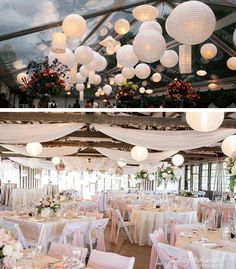 the inside and outside of a wedding reception with white paper lanterns hanging from the ceiling