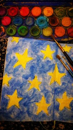 an art project with watercolors and paint on paper that has stars painted on it