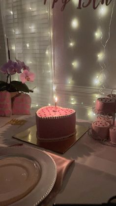 a pink birthday cake sitting on top of a table