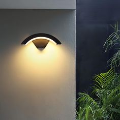 a wall light that is on the side of a building next to a potted plant