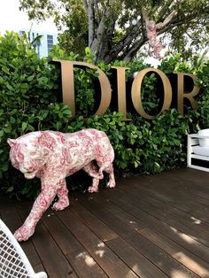 a pink pig statue sitting on top of a wooden floor next to a sign that says dior