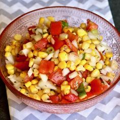 a glass bowl filled with corn and tomatoes