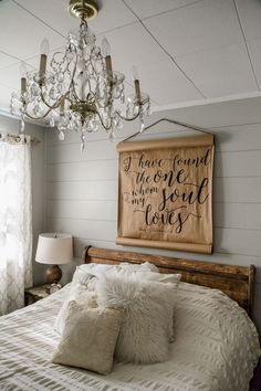 a bedroom with a bed, chandelier and two pillows on the pillowcase