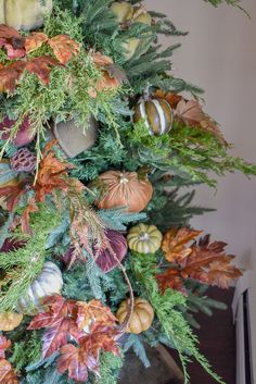 a christmas tree decorated with pumpkins and greenery