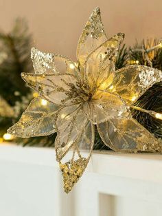 a gold and silver poinsettia sitting on top of a mantle