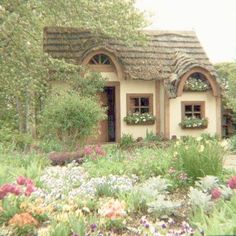 a house with flowers in front of it and trees around the window sills