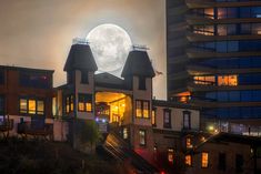 the full moon shines brightly over some buildings