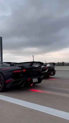 a black sports car driving down the road with red lights on it's side