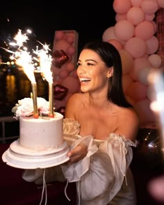 a woman holding a cake with sparklers on it