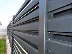 the side of a metal fence with grass in the background