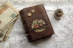 a brown leather journal sitting on top of a table next to money and a pen