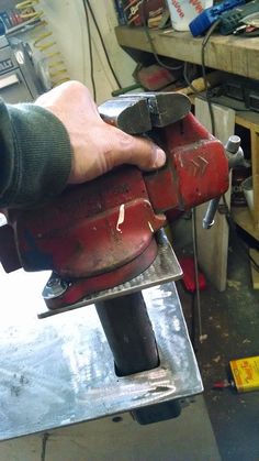 a person using a power tool on a piece of metal in a shop with other tools