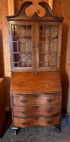 an old wooden desk with glass doors and drawers