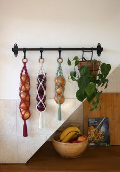 a bowl of fruit sitting on top of a wooden table next to a shelf with hanging macaroni and cheese