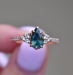 a woman's hand holding a blue and white diamond ring