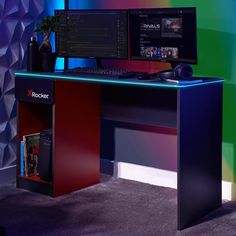 a computer desk with a monitor, keyboard and mouse on it in front of a colorful wall