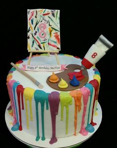 a birthday cake decorated with colorful icing and art supplies on it's side