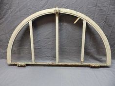 an old arched window with white paint on the bottom and sides, set against a gray background