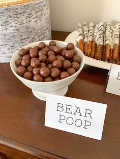 a table topped with bowls filled with chocolate covered donuts and pastries next to paper signs that say bear poop