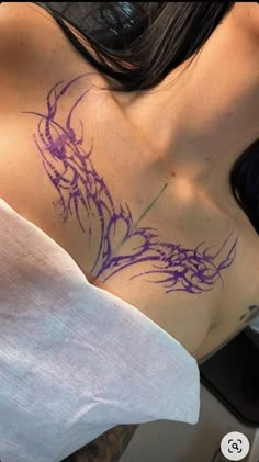 a woman's chest with purple ink on her left shoulder and right breast area