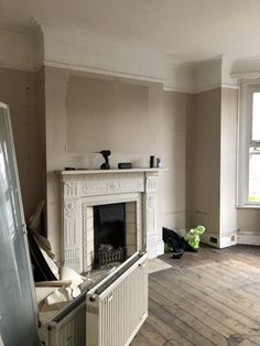 an empty living room with a fireplace and radiator in the middle of it