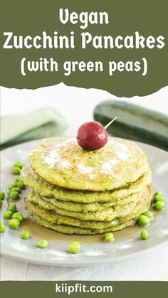 vegan zucchini pancakes with green peas on a white plate topped with a cherry