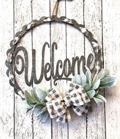 a welcome sign hanging on the side of a wooden wall with greenery and a bow