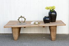 two vases sitting on top of a wooden table next to a vase with flowers