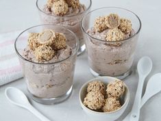 three desserts in small glass bowls with spoons next to them