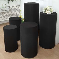 four black round tables and stools in a room with white flowers on the floor