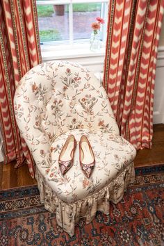 a pair of shoes sitting on top of a chair in front of a window