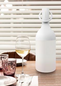 a wine glass and bottle sitting on a table next to a plate with utensils