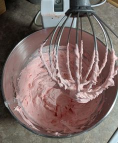 a mixer filled with pink frosting on top of a counter