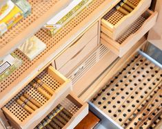 cigars are lined up in wooden boxes on shelves with pegs to hold them