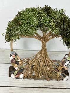 a bonsai tree with lots of leaves and rocks in it's base on a wooden table