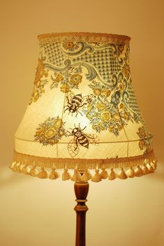 a lamp that is on top of a wooden stand with a white and gold shade