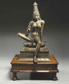 a bronze statue sitting on top of a wooden table