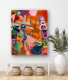 an abstract painting on a wall next to potted plants