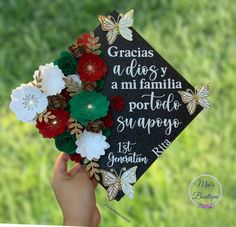 a graduation cap with flowers and butterflies on it is being held by someone's hand