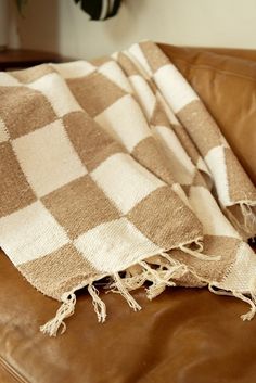 a brown leather couch with a checkered blanket on it