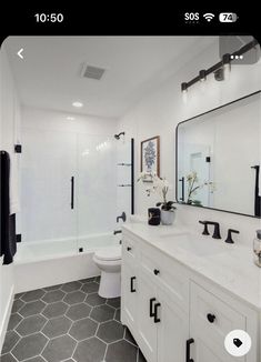 a white bathroom with black accents and tile flooring