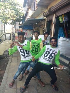 three men in green and white shirts posing for a photo on the sidewalk with their arms around each other