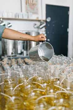 a person pouring some liquid into small plastic cups in a room full of empty glasses