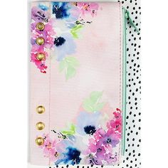 a pink and blue flowered notebook with gold buttons on the front, sitting on a polka dot background