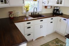 a kitchen with white cabinets and wood counter tops