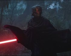 darth vader in the dark forest holding a red light saber and wearing a helmet