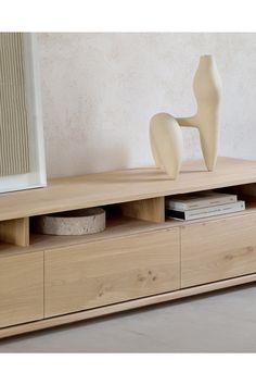 a white vase sitting on top of a wooden shelf next to a book case and mirror