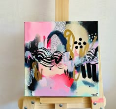 an easel with a painting on it and some paint splattered over the top